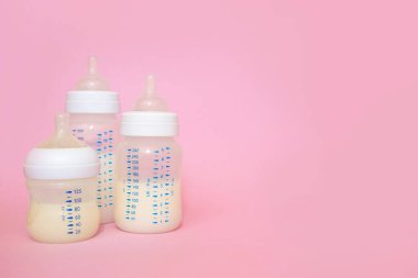 Pembe arka planda bir bebek için bir şişe süt..