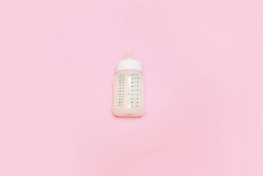 Pembe arka planda bir bebek için bir şişe süt..