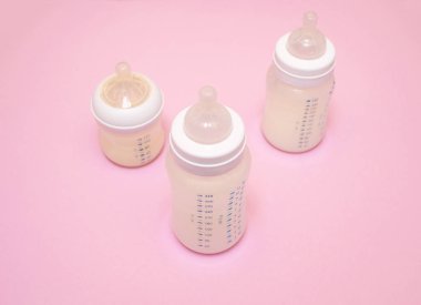 Pembe arka planda bir bebek için bir şişe süt..