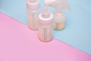 Pembe arka planda bir bebek için bir şişe süt..