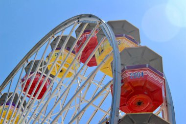 Mavi gökyüzü arkaplanlı, parlak bir dönme dolap manzarası.