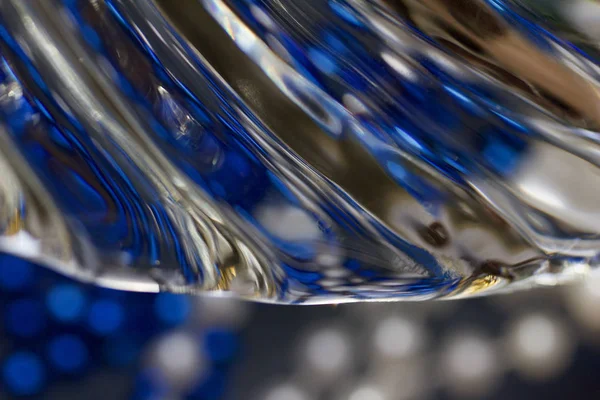 Modern kurşun kristal cam dokusunun soyut sanat arka planında sıvı benzeri bir girdap tasarımı var. Renkli bokeh ile parıldayan doğal ışığı yansıtıyor.