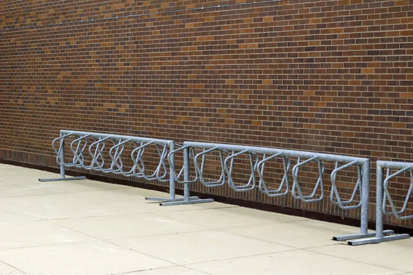 Geleneksel kahverengi tuğla duvar dokusu, temeli boyunca sağlam fırçalanmış metal bisiklet askıları