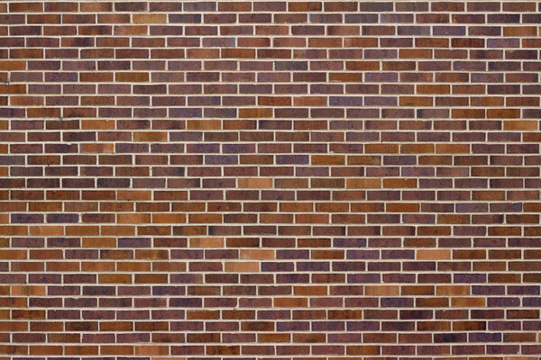 Traditional vintage brown brick wall texture background with bricks in varying shades of brown, red, blue, and purple