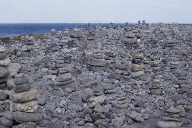 İrlanda 'da bir plaj boyunca yığılmış taşların, elle istiflenmiş düz taşlar ve çakıl taşlarının manzara manzarası