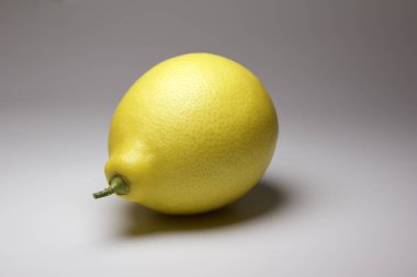 Tarafsız bir arkaplanda toplanmış tek bir sarı Meyer limonunun yakın görüntüsü.
