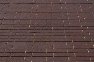 Çekici, mor tuğla duvar dokusu arka planının düşük açılı görüntüsü, tırmık gibi bir sedye tuğla kalıbında.