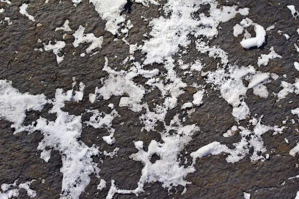 アスファルト路面上の雪のほこりの抽象的なテクスチャビューを閉じます — ストック写真