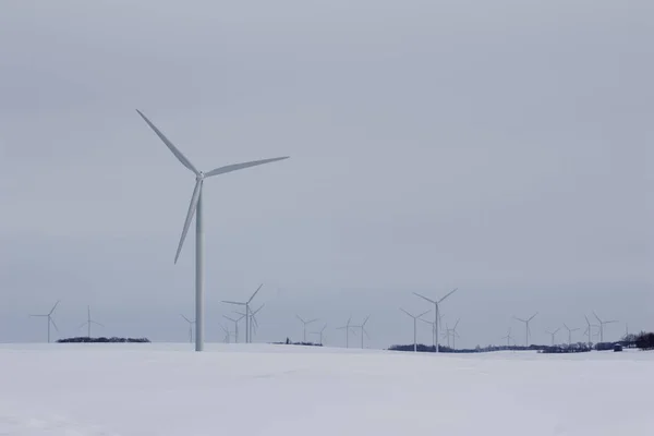 Landscape view of giant wind turbines in a snowy rural agricultural setting