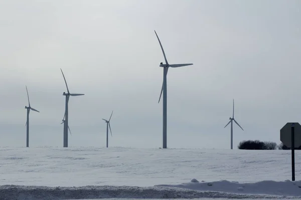 Landscape view of giant wind turbines in a snowy rural agricultural setting