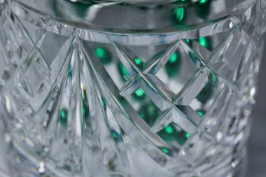 Metalik yeşil boncuklar içeren el yapımı kristal bir kavanozun yakın görüntüsü.