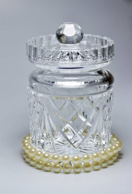 Modern bir el yapımı kurşun kristal kavanozu ve beyaz arka planda bir dizi inciyle süslenmiş kapağı yakından izleyin.