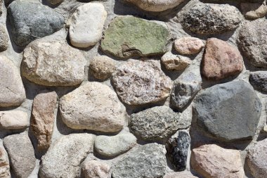 Değişen şekil ve boyutlarda renkli engebeli taşlarla doğal kaya duvar dokusu