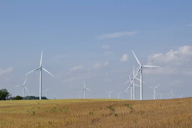 Dev rüzgar gücü türbinlerinin mavi gökyüzü arka planına sahip bir tarımsal alan üzerindeki peyzaj görüntüsü, kopyalama alanı ile