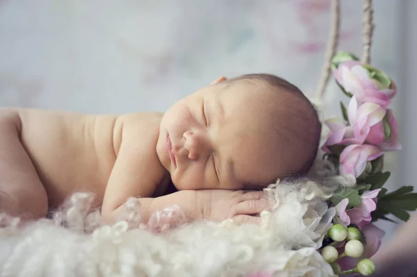Çiçekli düş kapanı içinde yeni doğmuş bir bebek. Çiçek ve gül çiçeğiyle sallanıyor. 