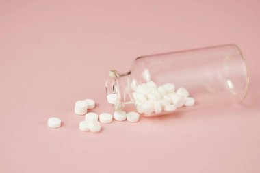 Cam şişelerde beyaz tıbbi haplar, pembe arka planda yakın plan. Fotokopi makineleriyle tıbbi hazırlıkların yakın plan fotoğrafı.