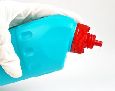 Beyaz arka planda lastik beyaz eldivenli mavi plastik şişe. Oda ve evleri temizlemek ve dezenfekte etmek için sıvı. Yakın plan..
