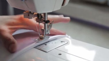 Dikiş makinesine beyaz kumaş dikiyorum.