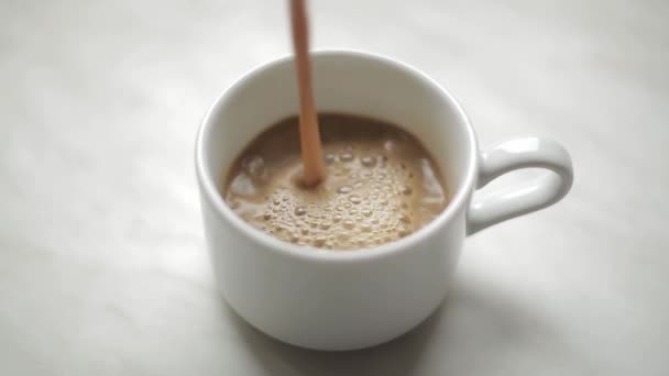 Café avec du lait est versé dans une tasse