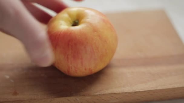 Vrouwelijke Hand Draait Een Hele Appel Een Snijplank — Stockvideo