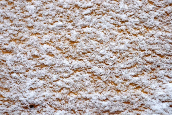 Light brown furniture covered with fluffy snow. Snow texture on a light tree.