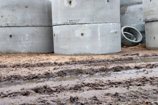 Puddle, dirt and cement rings for piping. Concrete building materials. Construction