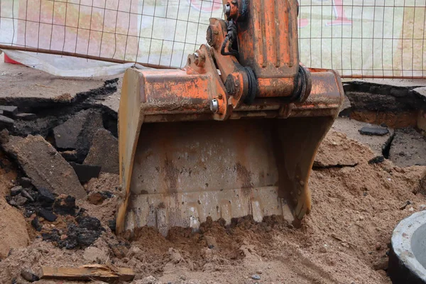 Excavator bucket breaks the asphalt. Excavator bucket in the ground