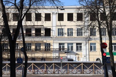 Kırmızı ışık, ağaçlar, penceresiz bina ve cadde. Bina onarımı.