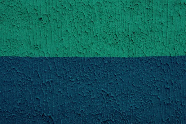 The relief of the cement wall in two colors - blue and mint. Surface in blue and mint color divided in half