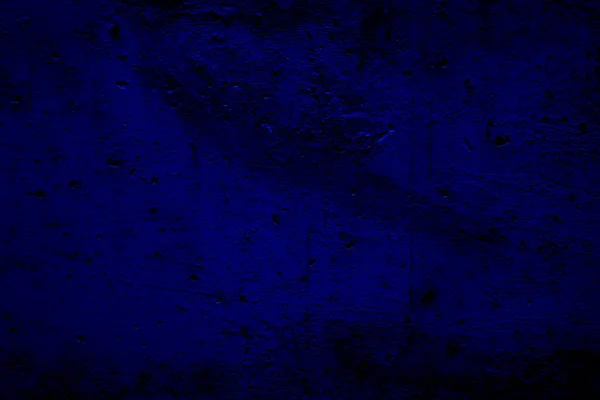Grungy uneven dark blue background with dimming. Dark blue uneven surface with holes for design and text.