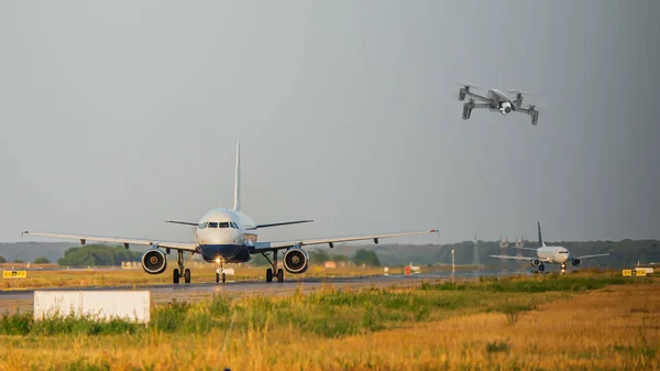 Uluslararası havaalanında taksicilik yapan ticari jet uçaklarının yanında uçan insansız hava aracı. Havacılık tehlikesi olası bir çarpışma nedeniyle uçuşlarda bozulma ve gecikme - birleşik görüntü