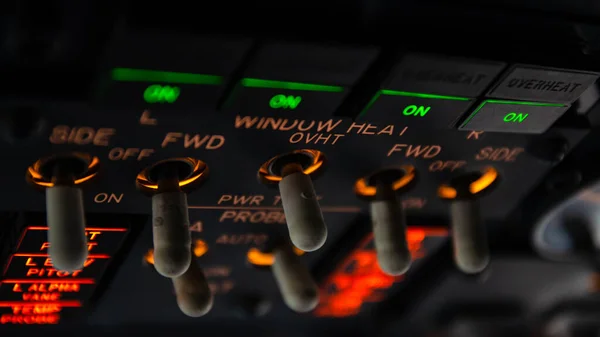 Büyük bir uçak kokpitinin üst panelindeki pencere ısısı anahtarlarının detaylı görüntüsü. Modern ticari jet uçuş güvertesinin güzel detaylarıyla seçici bir odak.