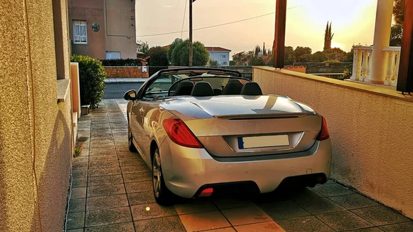 Spor üstü açık araba garaj yolunda park edilmiş. Arka planda güzel gün batımına karşı tepesi açık keyifli bir sütundu.
