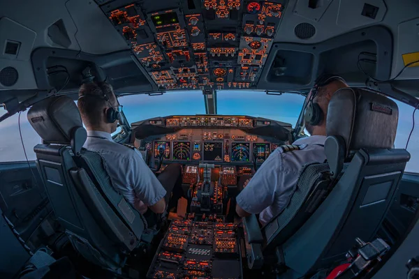 Pilotlar uçuş sırasında uçuş güvertesinin penceresinden içeri giren ilk güneş ışınlarıyla jet ticari uçaklarının kokpitinde.