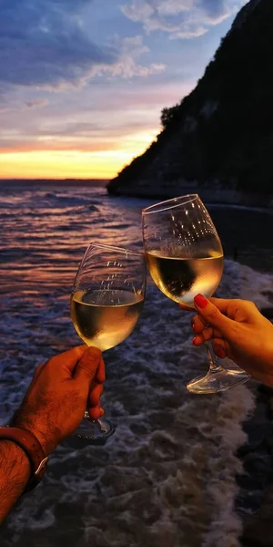 Aşık genç çift gün batımında plaj barında romantik bir akşam yemeği sırasında köpüklü şarap içiyor. Şampanyayla düğün kutlaması.