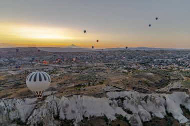 Güneş doğarken Goreme, Kapadokya 'daki volkanik bacaların üzerinden sıcak hava balonu uçuşu. Peri gibi uçuşan renkli sıcak hava balonları çevre ve ışık gibi