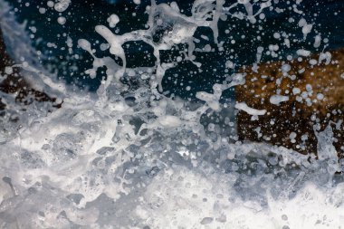 Kıyı kayalıklarında köpük ve spreyle sörf dalgaları kopuyor..