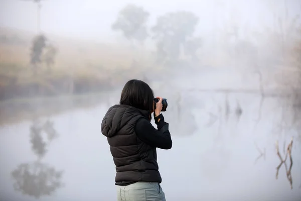 Women photographer holding a camera in the wild near river and h — Zdjęcie stockowe