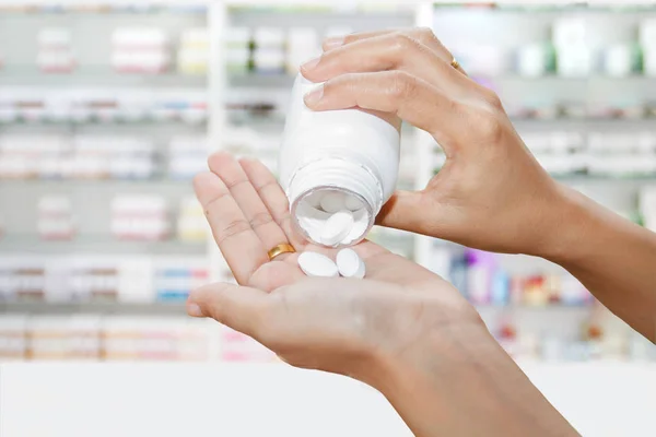 Mano del médico sosteniendo la botella de la medicina en el gabinete de la medicina y s — Foto de Stock