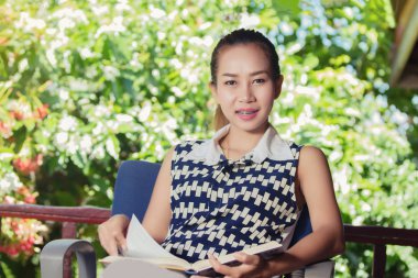 Asyalı kadın bahçe dinlenmek için bir kitap okuma .