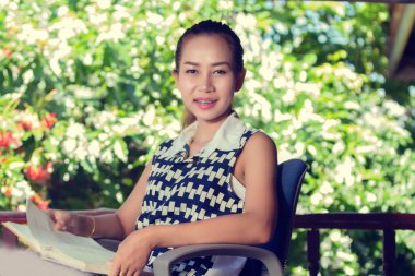 Asyalı kadın gevşeme vintage için bahçede bir kitap okuma 