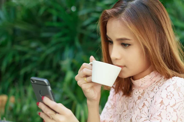 Asiatiska affärskvinnor använder mobiltelefon och dricka kaffe på c — Stockfoto