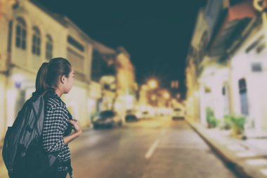 Asyalı kadın karanlık gecede, vintage tarzı sırt çantası ile seyahat