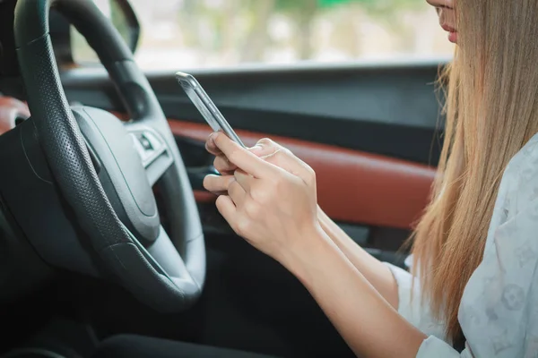 Las mujeres asiáticas están conduciendo coches y utilizando un teléfono inteligente en la carretera . — Foto de Stock