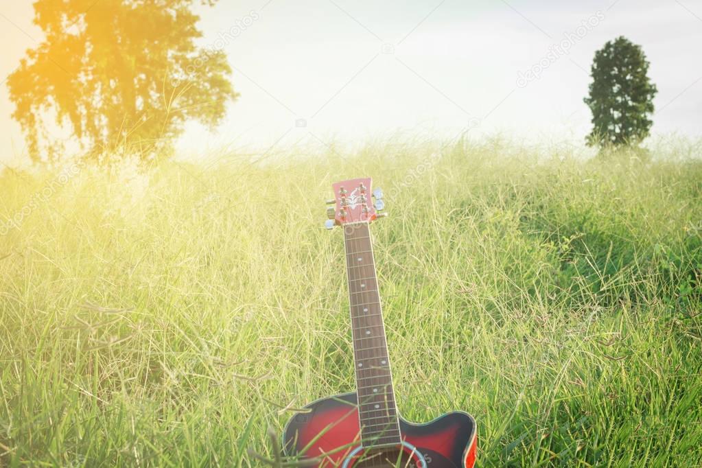 blurry and soft focus of guitar on grass at sunset 