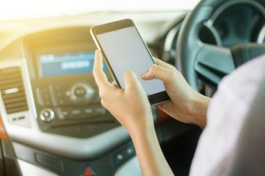 Asyalı kadınlar araba sürüş ve yol üzerinde bir smartphone kullanarak.
