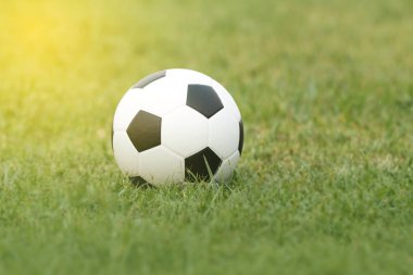 Futbol topu ve futbol günbatımında çimenlerin üzerinde