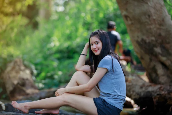 La chica está sentada en una cascada y sonriendo feliz —  Fotos de Stock