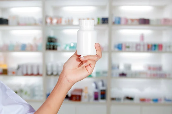 Hand des Arztes hält Medikamentenflasche auf Medizinschrank und s — Stockfoto