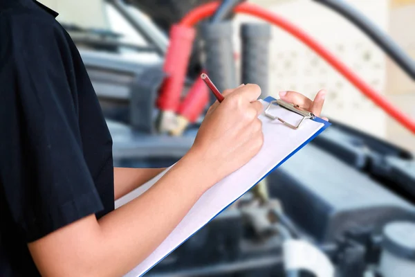 Retrato de una joven mecánica sonriente inspeccionando un coche en —  Fotos de Stock